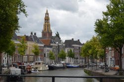 The Aa-kerk in Groningen with old buildings and trees and a canal filled with boats in the foreground