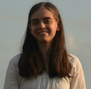 A young woman with medium-length brown hair wearing a beige blouse